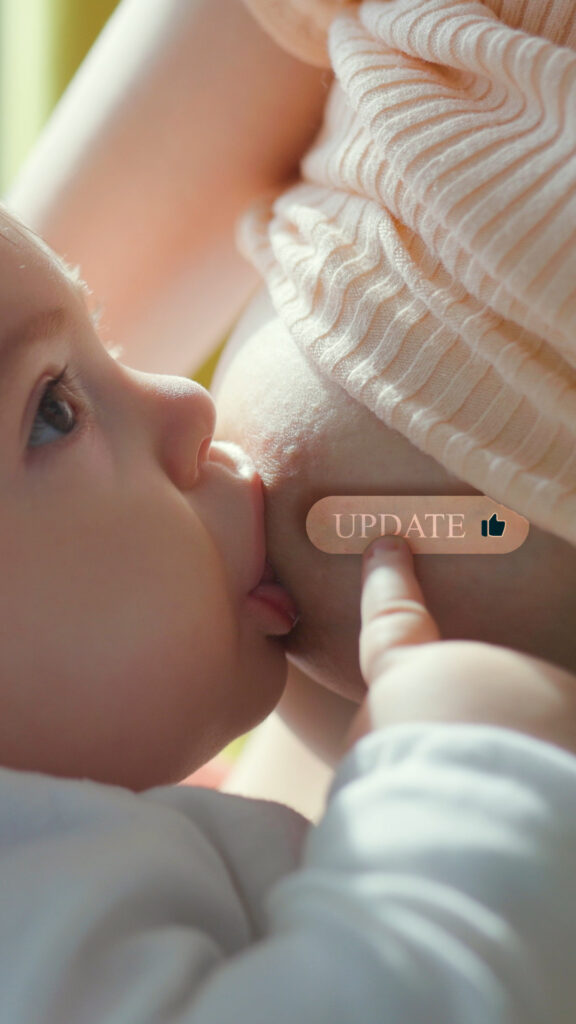 A baby breastfeeding and pushing an update button on her mother's breast